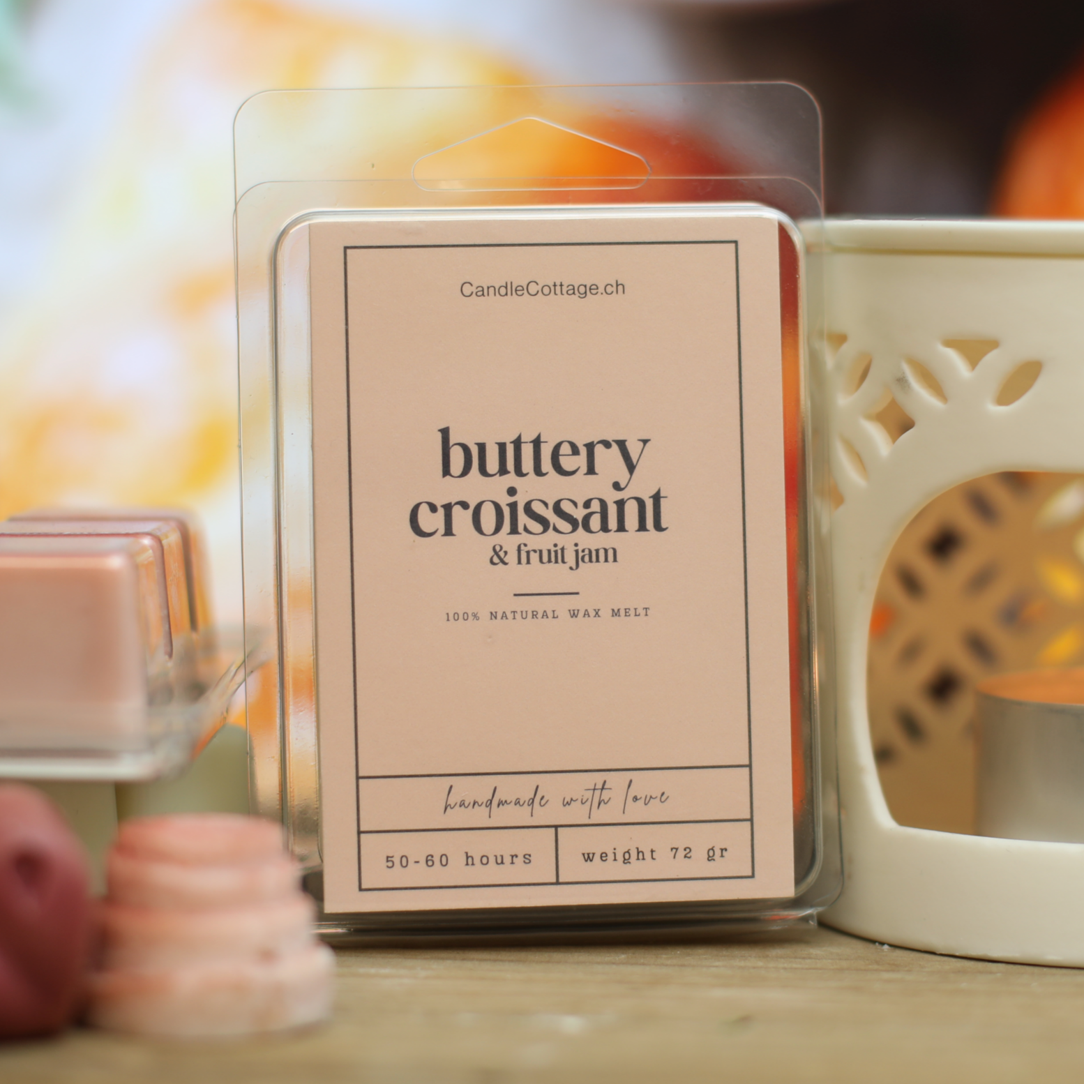 Buttery croissant and fruit jam wax melts packaging on wooden table with candle holder.
