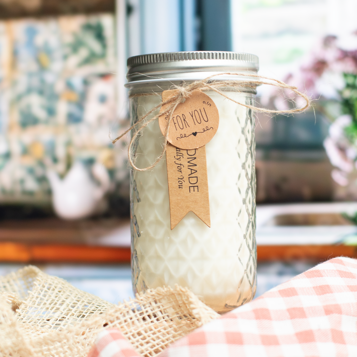 Ms. COTTI Lililee scent candle in a glass jar with a rustic label, placed on a checkered cloth, evoking a cottage charm.